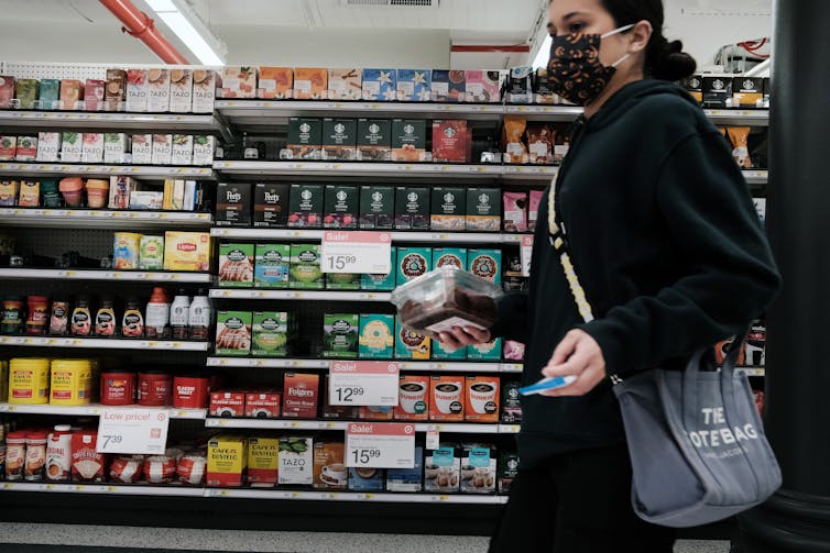 A woman is seen shopping at a grocery store during a time of inflation and higher prices for gas and food.