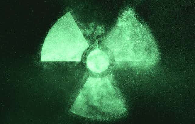 A radiation symbol glowing faintly green on a dark background