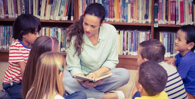 Woman in library reading story to children