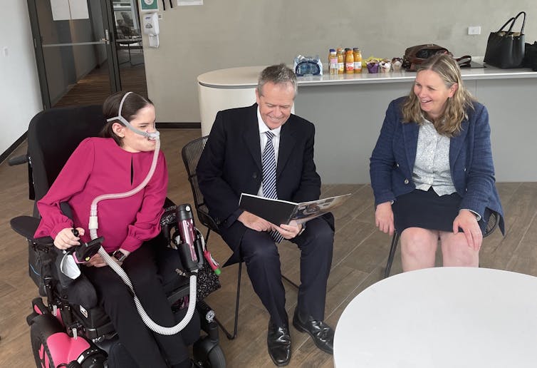 three people gather, one reading a document