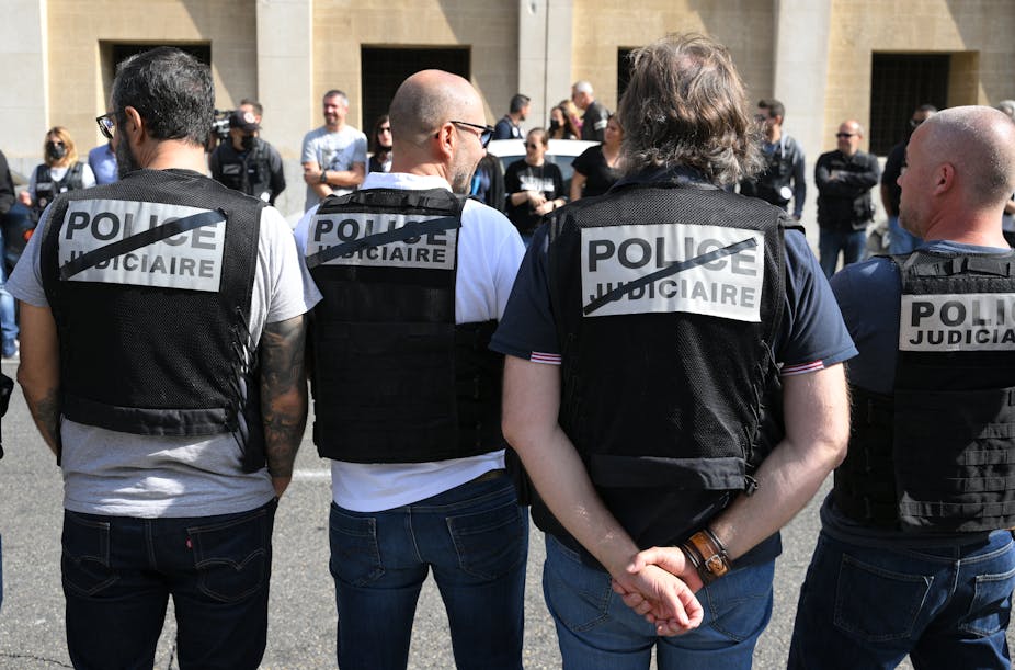 Des membres de la "Police judiciaire" française se tiennent en rang pour former une garde d'honneur afin de montrer leur soutien au directeur de la police judiciaire Eric Arella après qu'il ait été démis de ses fonctions, devant leur siège pour le district sud, à Marseille, dans le sud de la France, le 7 octobre 2022.