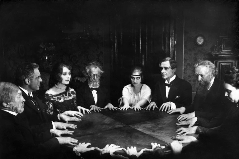 A group of people in 1920s dress around a table.