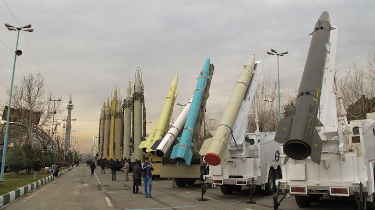 A line of missiles on the back of mobile launchers on a city street