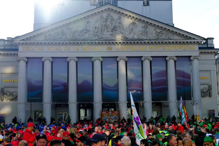 Protestors holding banners outside a government building in Brussels.
