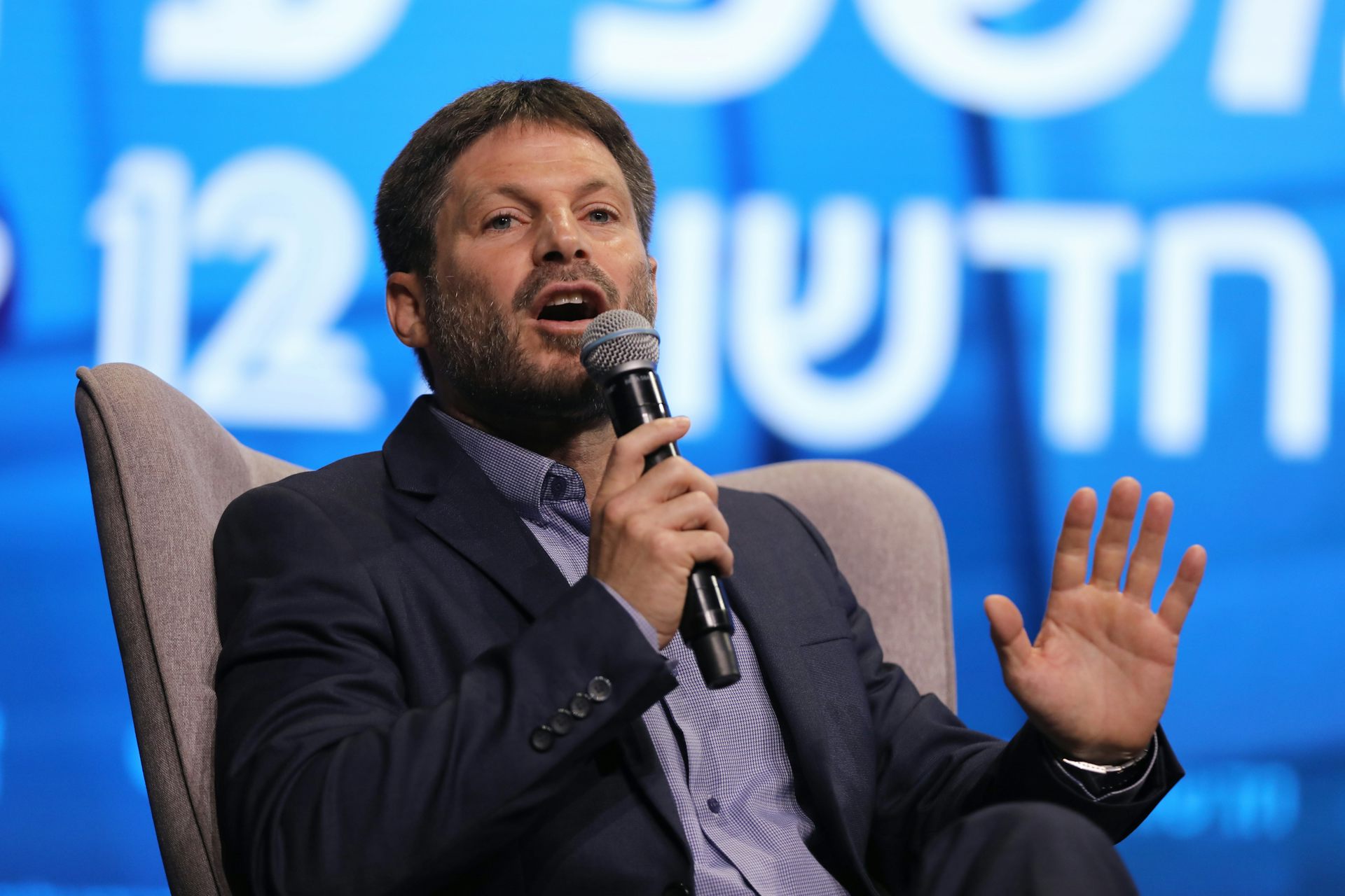 Bezalel Smotrich, the leader of the Religious Zionist Party, holds a microcphone as he speaks in a TV debate.