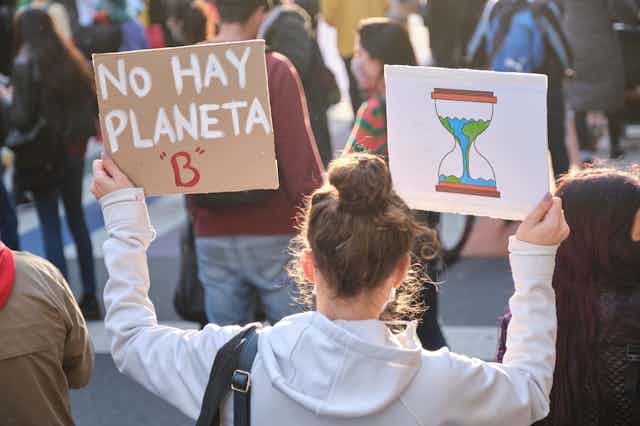 Chica de espaldas sujeta una pancarta que dice: "No hay planeta B".