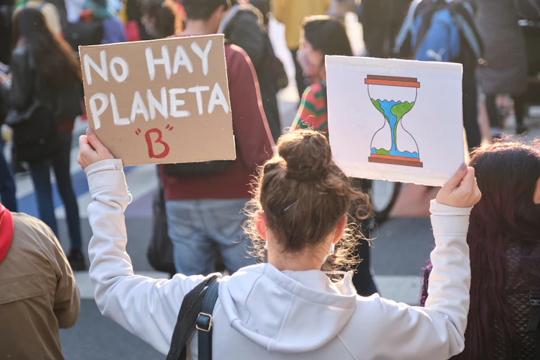Chica de espaldas sujeta una pancarta que dice: "No hay planeta B".