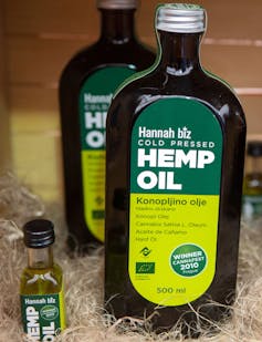 A brown glass bottle of hemp oil with a green label sitting in some packing straw.