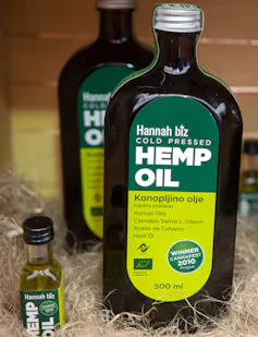 A brown glass bottle of hemp oil with a green label sitting in some packing straw.