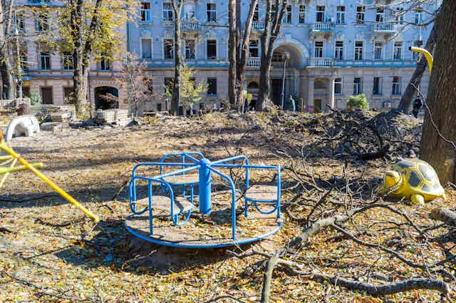 A children's garden in Kyiv after a Russian missile strike. In the foreground is a damaged roundabout.