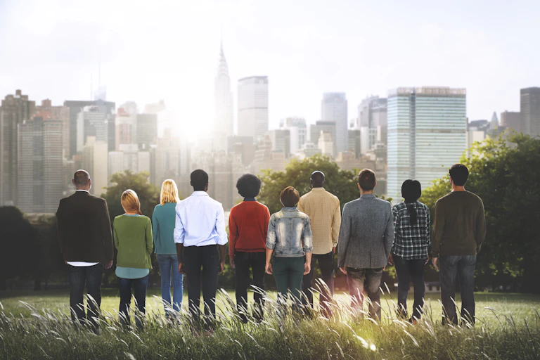 A row of people standing with their backs to the camera facing a city in the distance