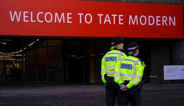 Police officers seen in front of  a red sign that says Welcome to Tate Modern.