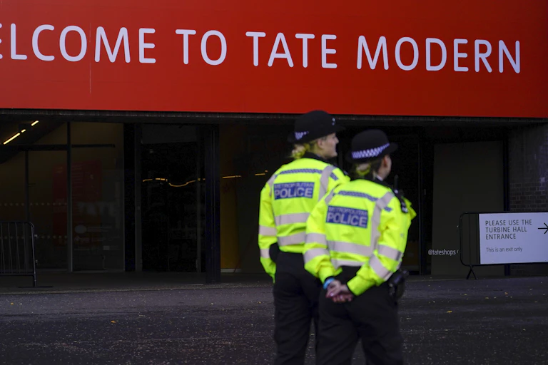 Police officers seen in front of a red sign that says Welcome to Tate Modern.