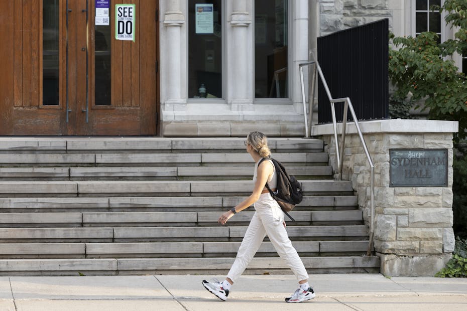 A student seen walking past a building with steps.