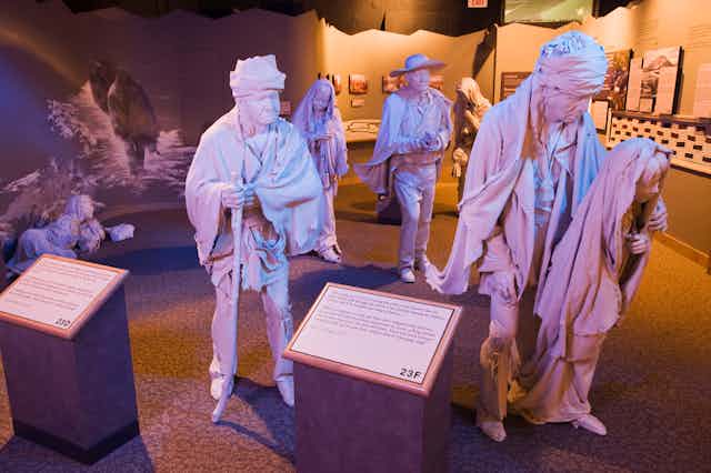 A museum exhibit shows seven life-size sculptures of Native American adults and children.