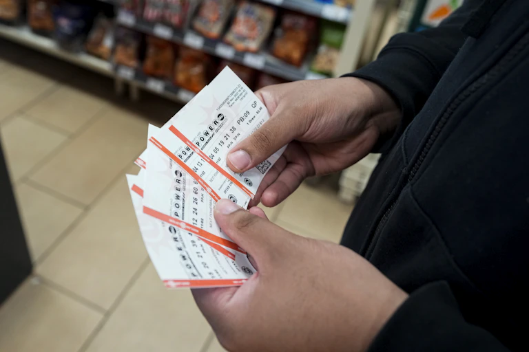 close up of white hands holding several lottery tickets in a convenience store
