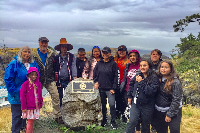A group of people stand around a rock with a plaque.