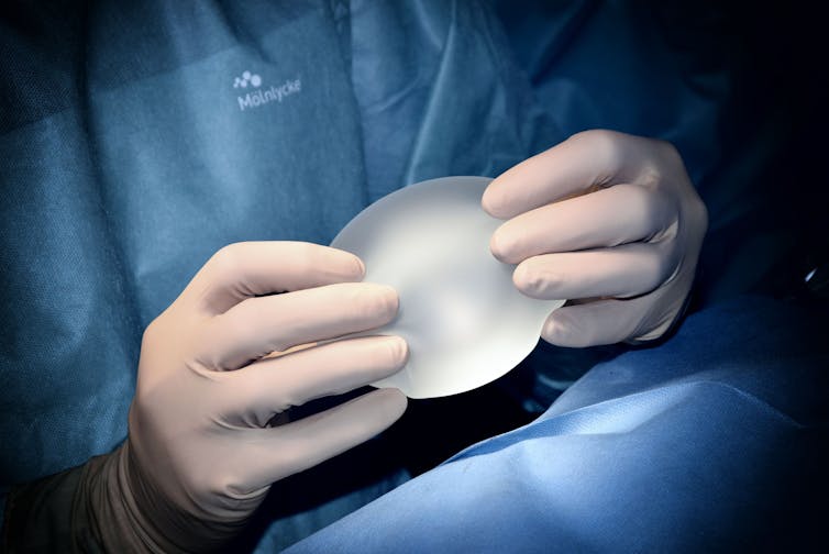 Surgeon holding a breast implant