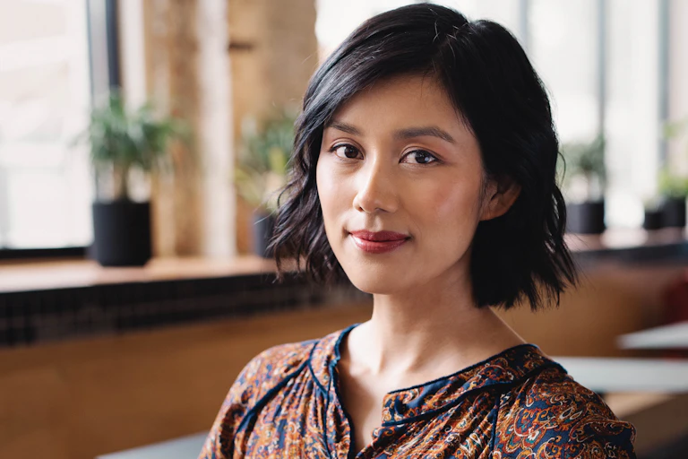 a beautiful Vietnamese Australian young woman with a bob and red lipstick, and a hint of a smile