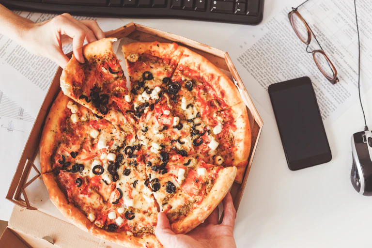 People sharing a takeaway pizza at work desk