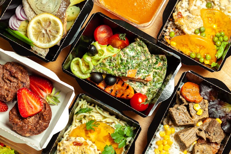 An assortment of meals in black takeaway boxes.
