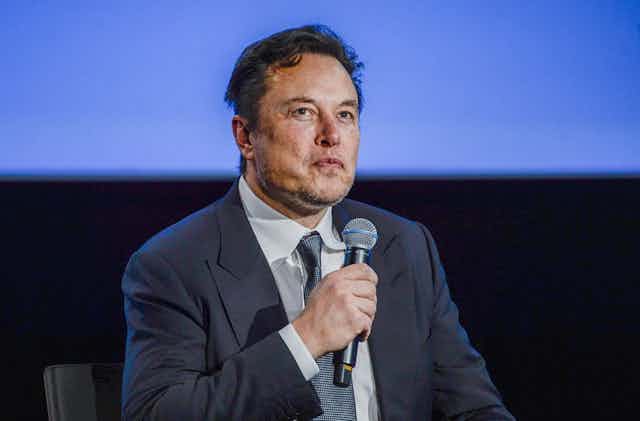 Elon Musk holding microphone.