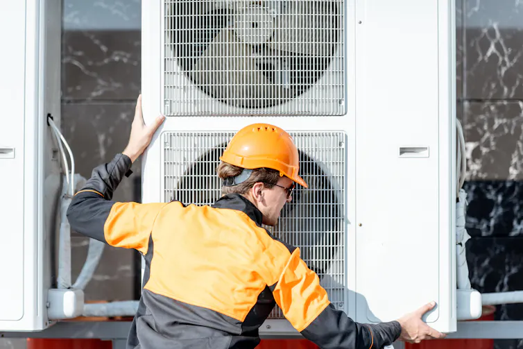 An engineer installs a heat pump.