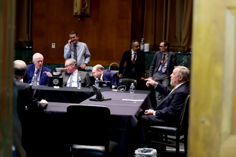 A group of men in suits are gathered around a group of tables.