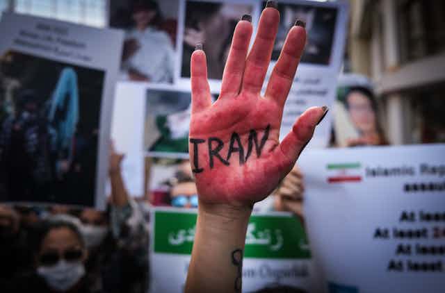 Iranian people hold pictures of Mahsa Amini with their hands painted in red during a protest outside the Iranian Consulate in Istanbul, October 2022.