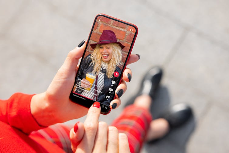 A top view of a woman scrolling on tiktok, with an influencer on the screen