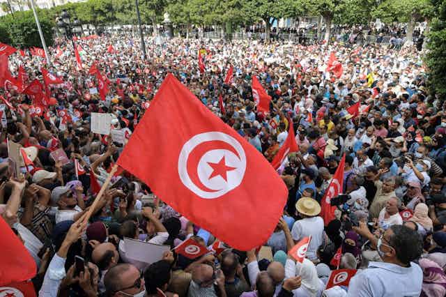 Massed protesters wave Tunisian flags in a town square