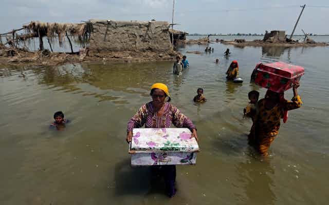 Women carry belongings salvaged from their flooded home after monsoon rains, in the Qambar Shahdadkot district of Sindh Province, Pakistan on Sept. 6, 2022. 