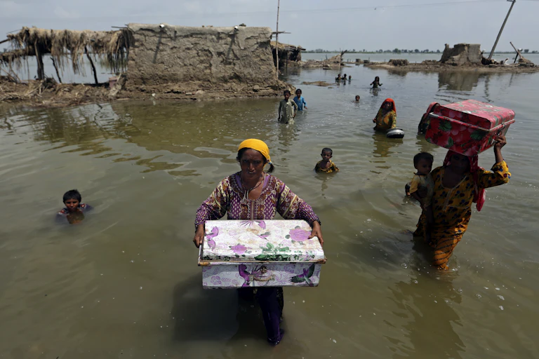 Women carry belongings salvaged from their flooded home after monsoon rains, in the Qambar Shahdadkot district of Sindh Province, Pakistan on Sept. 6, 2022.