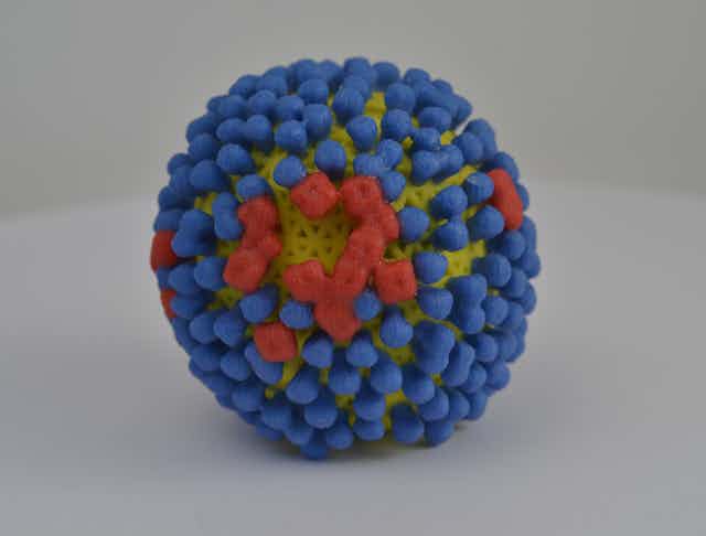 A round model with mostly blue studs and few red studs against a yellow surface.