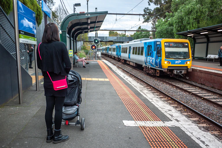 woman with pram waiting for train at suburban railway station
