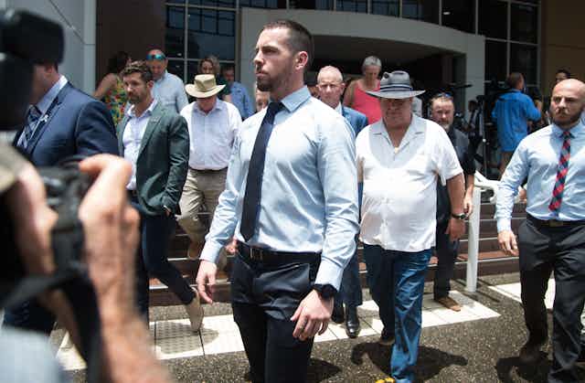 Zachary Rolfe, a white man in a shirt and tie, stands outside a courthouse.