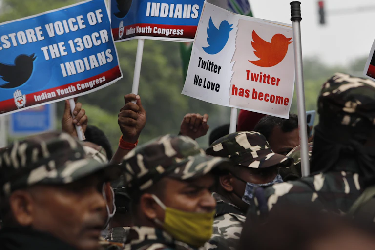 A photo of protesters in camouflage gear holding signs criticising Twitter.