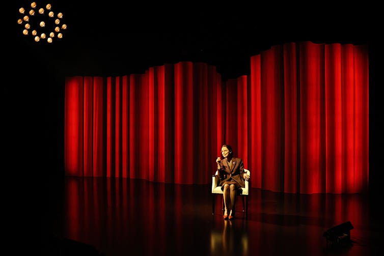 A big red stage with a single chair.
