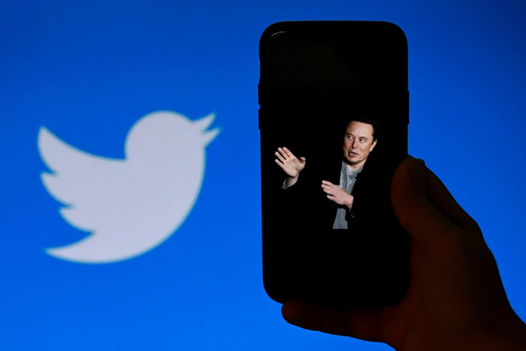 Logo Twitter à côté d'un smartphone sur lequel s'affiche Elon Musk.