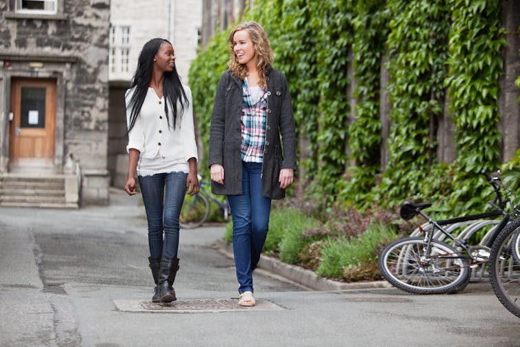 Two young adult women go for a walk in the city.