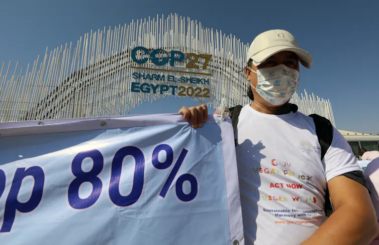 A protester holds a banner before the entrance of the COP27 conference.