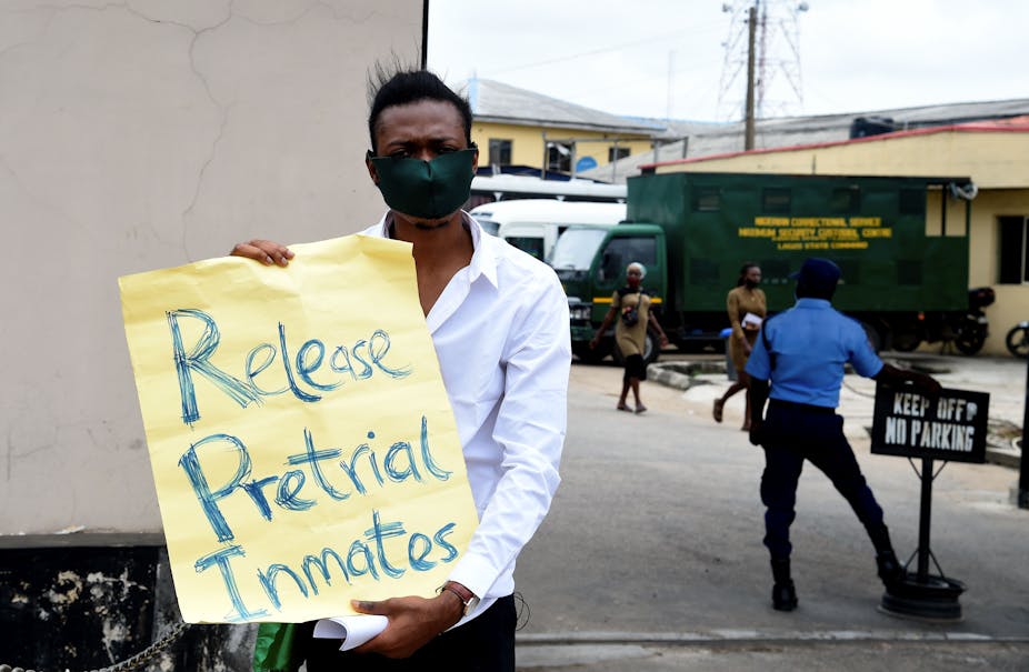 Man standing outside holding a placard written Release Pretrial Inmates.
