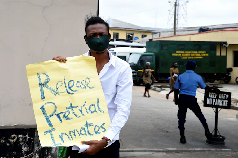 Man standing outside holding a placard written Release Pretrial Inmates.