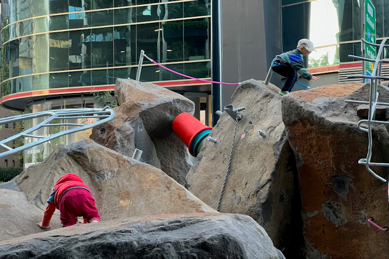 Kids climb over boulders