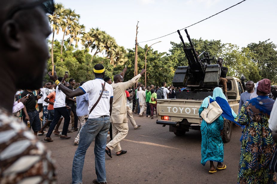 People cheering on soldiers on a gun-mounted vehicle