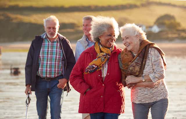 Four adults with gray hair walking outdoors