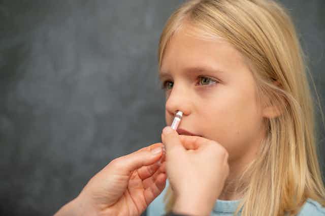A child receives a nasal vaccine.