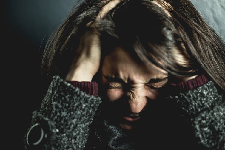 A woman grasps her head in fury.