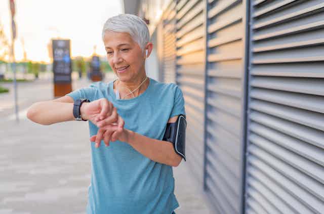 A photo of a woman wearing a smartwatch and heart rate monitor armband.