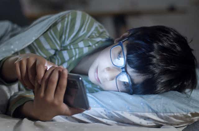 boy in bed looking at phone